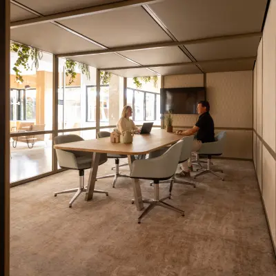 Interior view of a furnished office space at Luttenbergweg 8 in Amsterdam South East, featuring two people engaged in a meeting. This office space rental offers a comfortable environment for business activities.