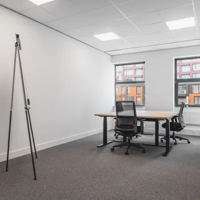 Office space for rent at Paasheuvelweg 20 in Amsterdam South East, featuring two desks and chairs with windows offering natural light.