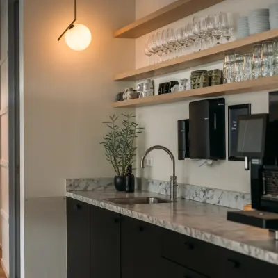 Interior of an office space for rent at Bos en Lommerplein 280, Amsterdam West, featuring a modern kitchen area with shelves, a sink, and cabinets.