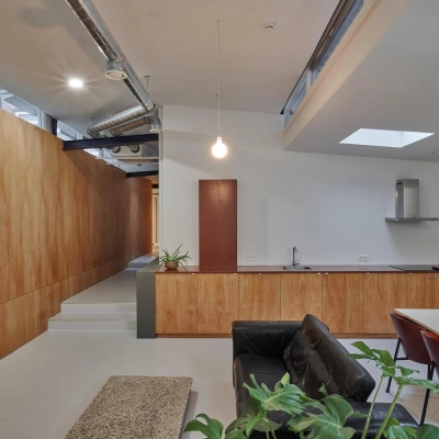 Modern office space with wood paneling and skylights at Hondiusstraat 7H in Amsterdam West, featuring a sleek kitchenette and a cozy seating area. Perfect for office space rental.