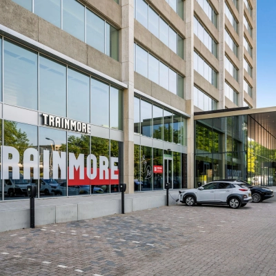 Exterior view of an office building at Nachtwachtlaan 20 in Amsterdam West, showing the street entrance and parking area for office space rental.