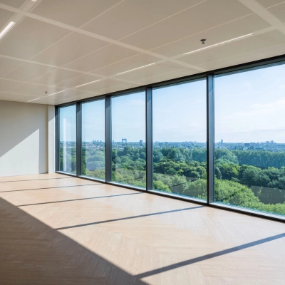 Spacious office area with large windows offering a panoramic view of greenery in Amsterdam West, perfect for office space rental.