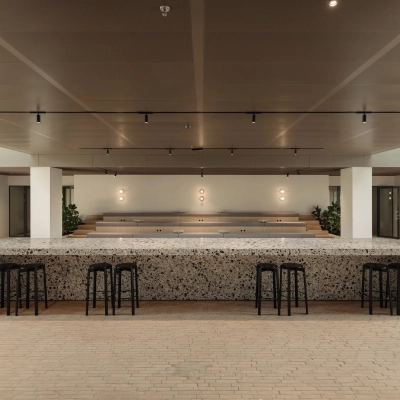 Modern office space in Amsterdam West at Nachtwachtlaan 20, featuring a spacious open area with a terrazzo table and bar stools, ideal for office space rental.