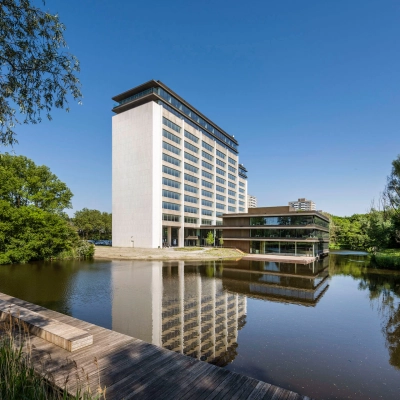 Exterior view of an office building at Nachtwachtlaan 20, Amsterdam West, ideal for office space rental, with a pond and surrounding greenery.