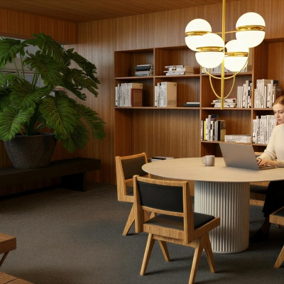 A furnished office at Barbara Strozzilaan 101, Amsterdam Zuidas, features wooden decor, bookshelves, a round table, and a person working on a laptop. Ideal for office space rental.