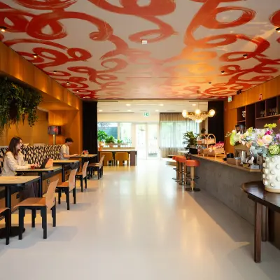 Lively office space rental with eclectic decor at Barbara Strozzilaan 101, Amsterdam Zuidas. Two people are working at tables in this furnished lounge area.