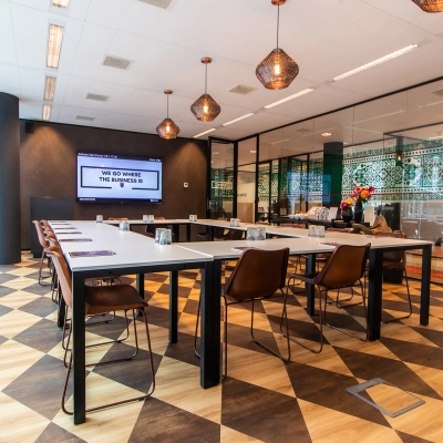 Modern office space for rent at Claude Debussylaan 7-29, Amsterdam Zuidas, featuring a stylish meeting area with geometric flooring, glass partitions, and trendy light fixtures.
