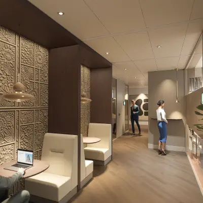 Modern office space at Claude Debussylaan 80-134 in Amsterdam Zuidas featuring stylish furnishings with individuals engaged in collaborative discussions and laptop work. Ideal for office space rental.