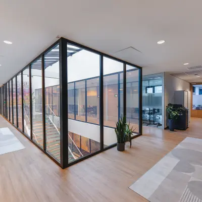 Modern office space at De Boelelaan 30, Amsterdam Zuidas, featuring glass walls, wooden flooring, and a view into conference rooms. Ideal for office space rental.