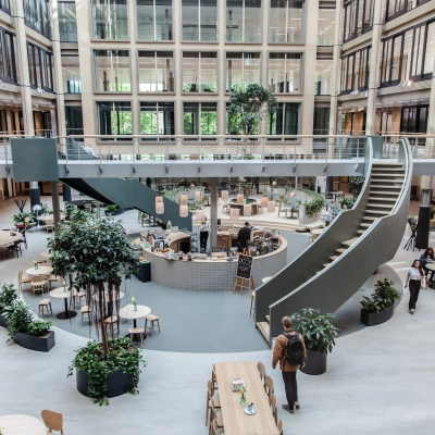 Spacious interior at Fred. Roeskestraat 100, Amsterdam Zuidas, showcasing an open floorplan with modern furnishings and individuals engaging in discussions and activities. Ideal for office space rental.