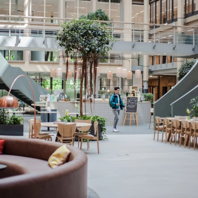 Open office space in Amsterdam Zuidas at Fred. Roeskestraat 100, featuring modern furniture and a central lounge area. People are engaged in business discussions and activities, adding to the vibrant atmosphere.