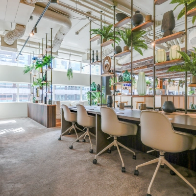 Bright and welcoming office space for rent at Gustav Mahlerlaan 308, Amsterdam Zuidas, featuring modern furnishings and open workstations with natural light and green accents.