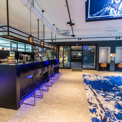 Modern office space for rent at Gustav Mahlerplein 28 & 58-60, Amsterdam Zuidas, featuring a stylish bar area with high stools and a vibrant carpet.