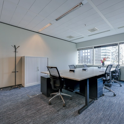 Bright office space with a large window offering city views, featuring a conference table and office chairs, perfect for meetings. Suitable for office space rental in Amsterdam Zuidas.