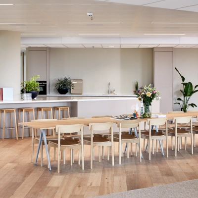 Spacious furnished office area in Amsterdam Zuidas, featuring a long table with chairs, bar stools, and a kitchenette. Ideal for office space rental at Hildegard Von Bingenstraat 44.