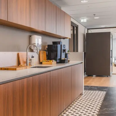 Modern office pantry in Amsterdam Zuidas at Hildegard Von Bingenstraat 44, featuring wooden cabinetry, a sleek countertop, and a coffee machine, perfect for office space rental needs.