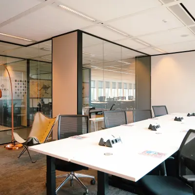 Modern office space in Amsterdam Zuidas with large conference table, comfortable chairs, and glass walls. Ideal for office space rental at Jachthavenweg 109.