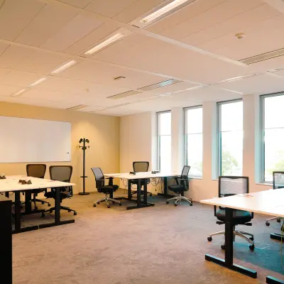 Furnished office space with several desks and chairs, well-lit by natural light, ideal for rent at Jachthavenweg 109 in Amsterdam Zuidas.