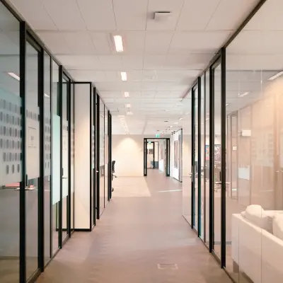 Modern office interior at Jachthavenweg 109, Amsterdam Zuidas, featuring glass-walled corridors ideal for office space rental.