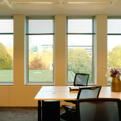 Bright office space at Jachthavenweg 109 in Amsterdam Zuidas featuring modern furnishings and large windows with a view of greenery. Ideal office to rent for a dynamic work environment.