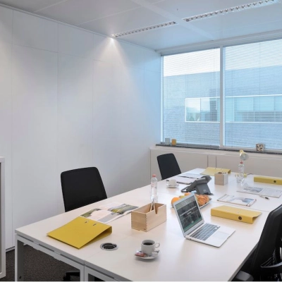 Bright office space with a large window, four desks, chairs, and office supplies in Antwerp Center, ideal for rent office space seekers.