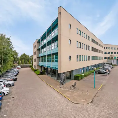 Exterior view of office space for rent at Lange Amerikaweg 55-61, Apeldoorn, featuring a large modern building with ample parking.