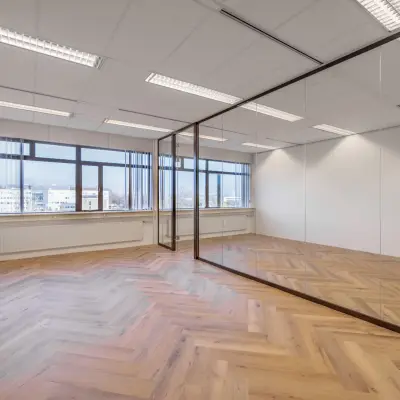 Spacious office for rent at Oude Apeldoornseweg 41-45, Apeldoorn featuring large windows and a wooden floor.