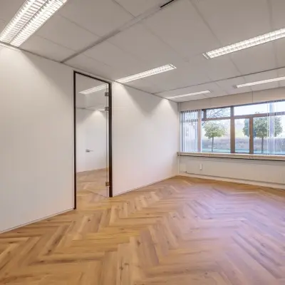 Bright office space with large window and wooden flooring, ideal for rent at Oude Apeldoornseweg 41-45, Apeldoorn.