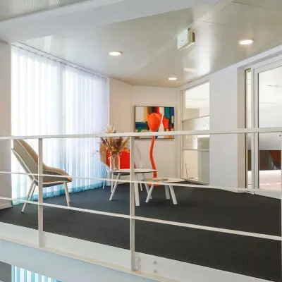 Bright, furnished workspace at Prins Willem-Alexanderlaan 301 in Apeldoorn featuring modern chairs and a table near tall windows.