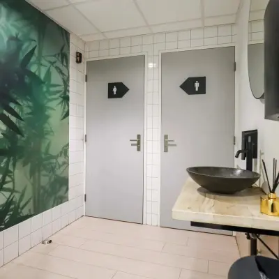 Interior view of a restroom with a modern sink, stylish wallpaper, and tiled walls at an office to rent in Prins Willem-Alexanderlaan 301, Apeldoorn.