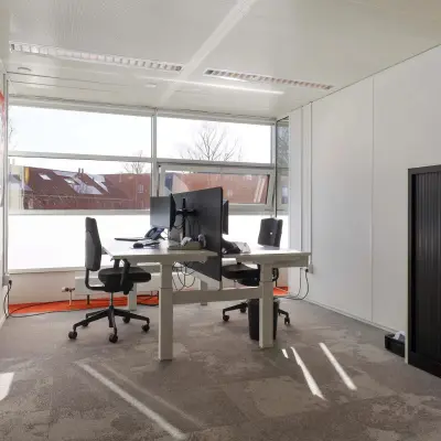 Bright office space with two desks, chairs, and a large window at Prins Willem-Alexanderlaan 301, ideal for office space rental in Apeldoorn.