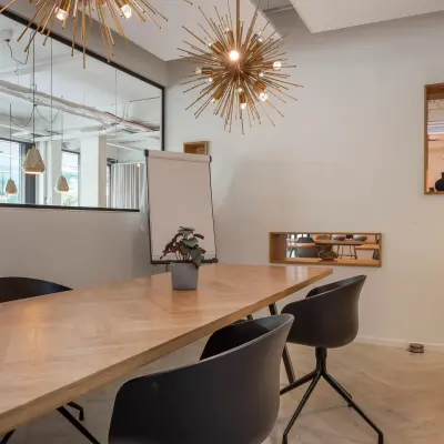 Modern office space at Roggestraat 111, Apeldoorn, featuring contemporary lighting and a wooden table with chairs, ideal for small meetings.