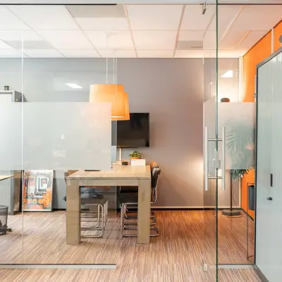 Modern office space to rent at Vlamoven 34, Arnhem IJsseloord, featuring a stylish meeting area with glass walls and warm lighting.
