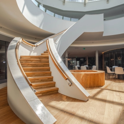 Bright and modern office space with a stylish wooden staircase and seating area, ideal for office space rental in Arnhem Zuid.