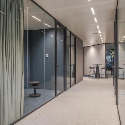 Modern office space for rent in Arnhem Zuid featuring glass-walled rooms with sleek furnishings and high ceilings.