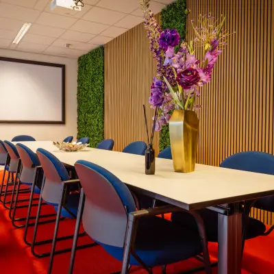 Furnished conference room with a long table and blue chairs at Amalialaan 126 in Baarn, available for office space rental.