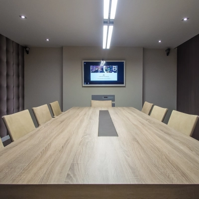 Modern conference room at Carrer d'Aribau 161, Barcelona Eixample with a large wooden table, cushioned chairs, and a wall-mounted screen, ideal for office space rental.