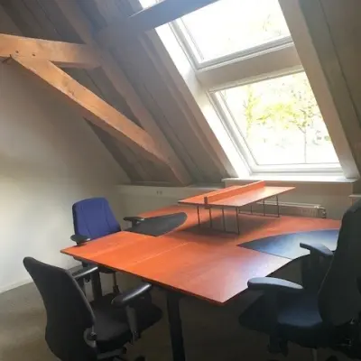 Office space with wooden beams, large windows, and several desks and chairs at Blokstallen 2B, Bergen op Zoom, ideal for office space rental.