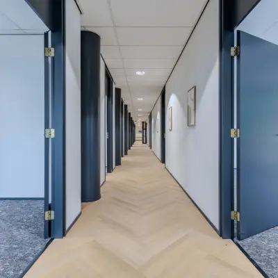 Modern hallway with open doors leading to various offices, ideal for office space rental at Rijtuigweg 10, Bergen op Zoom.