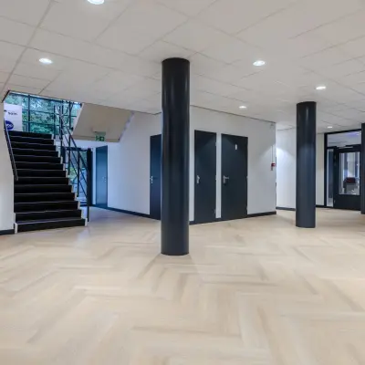Spacious interior of an office for rent at Rijtuigweg 10, Bergen op Zoom with sleek columns and modern flooring.