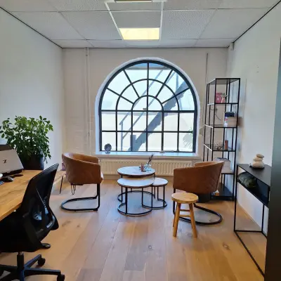 Bright office space at Zuidzijde Haven 39a, Bergen op Zoom, featuring a large arched window, wooden flooring, and modern furnishings, ideal for office space rental.