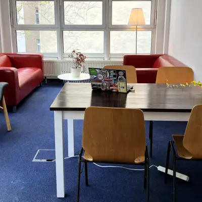 Office space in Berlin Kreuzberg with a table, chairs, and red couches, ideal for rent office space seekers.