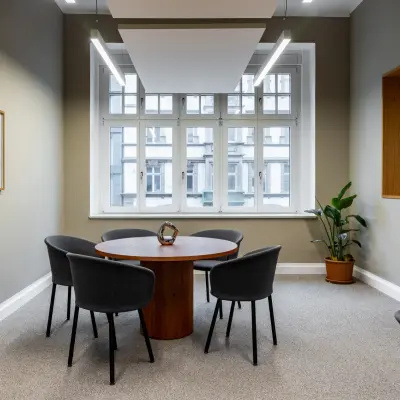 Bright office space for rent at Chausseestraße 29, Berlin Kreuzberg, featuring a round table with chairs beneath modern lighting, suitable for team meetings.