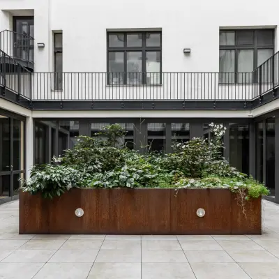 Courtyard view of office to rent at Chausseestraße 29, Berlin Kreuzberg, featuring a green plant installation surrounded by modern glass doors.