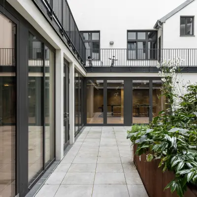 Exterior courtyard at Chausseestraße 29, Berlin Kreuzberg, showcasing modern glass facades and greenery. Ideal for those seeking office space rental with natural light.