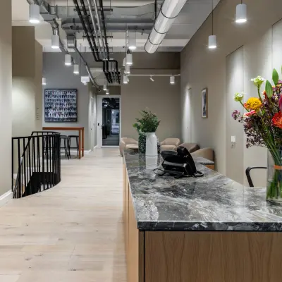 Office space rental with a stylish reception area featuring a marble desk and modern decor at Chausseestraße 29, Berlin Kreuzberg.
