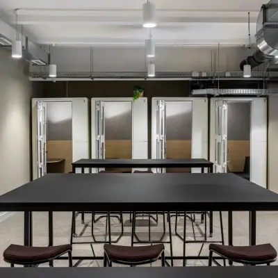 Modern office space to rent at Chausseestraße 29 in Berlin Kreuzberg, featuring sleek tables and chairs under industrial lighting.