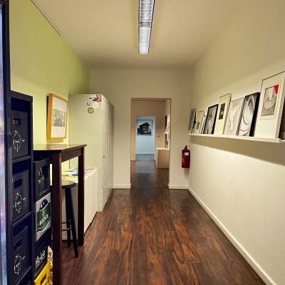 Interior hallway at An der Kolonnade 11, Berlin Mitte, featuring a vending machine, framed artwork, and dark wooden floors, ideal for finding office space rental in a vibrant area.