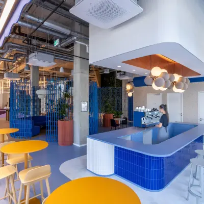 Modern office space at Heidestraße 34, Berlin Mitte featuring a vibrant coffee bar area with colorful seating, attractive lighting, and a person serving coffee. Ideal for office space rental.