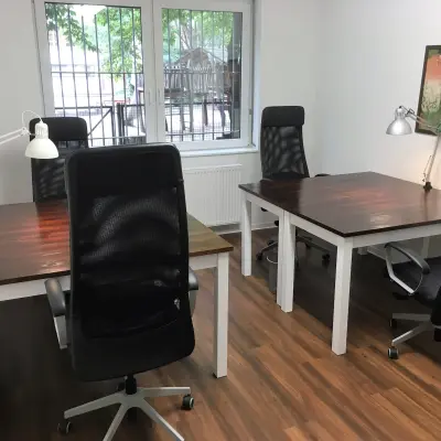 A furnished office space for rent at Jägerstraße 63 D in Berlin Mitte, featuring wooden desks, office chairs, and lamps, with a window view.